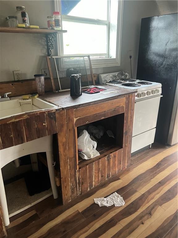 kitchen featuring dark hardwood / wood-style flooring, white gas range, fridge, and sink