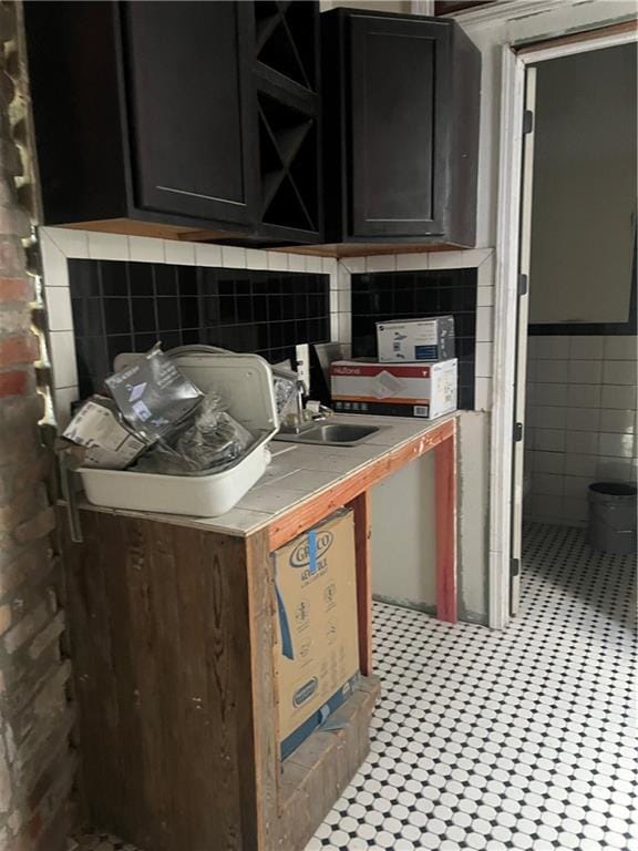 kitchen featuring light tile floors, tasteful backsplash, sink, and tile walls