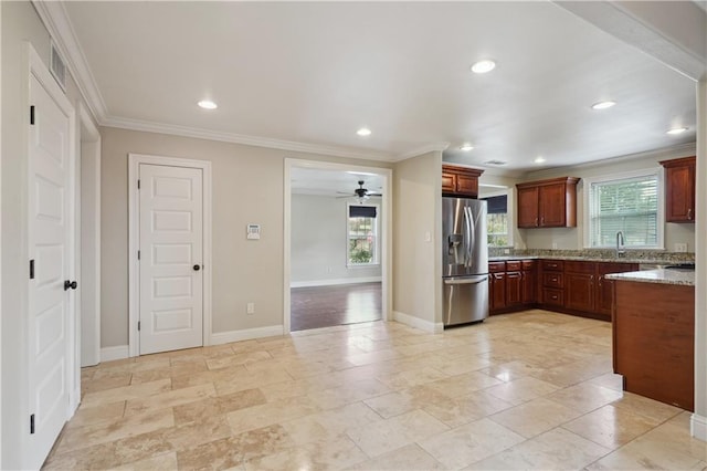 kitchen with sink, crown molding, stainless steel refrigerator with ice dispenser, ceiling fan, and light stone counters