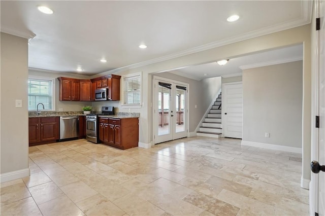 kitchen featuring light stone countertops, french doors, sink, crown molding, and appliances with stainless steel finishes