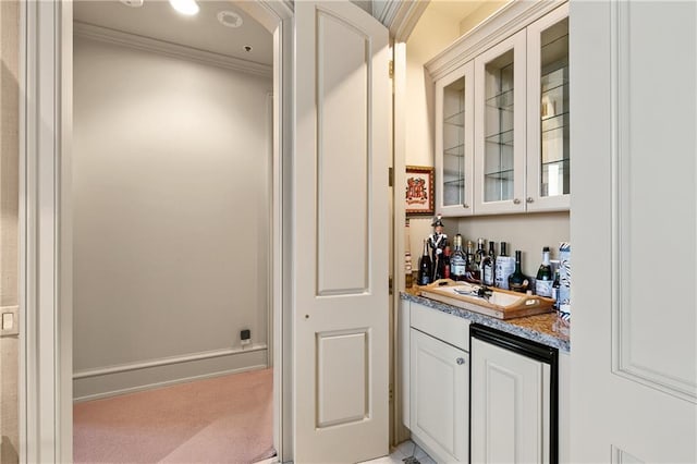 bar with light carpet, white cabinets, ornamental molding, and light stone countertops