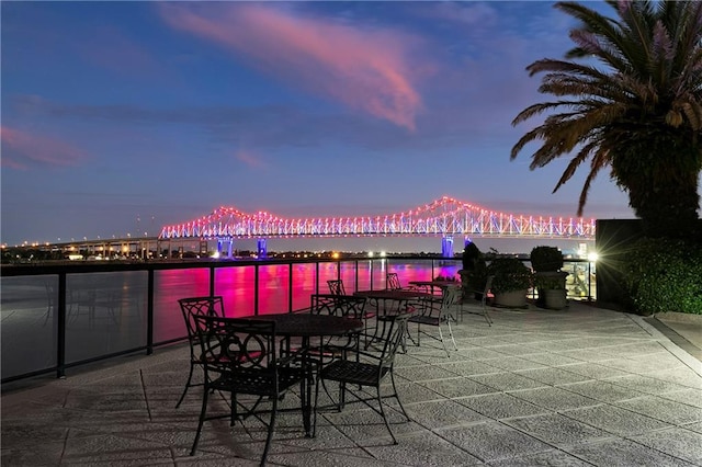 patio terrace at dusk featuring a water view