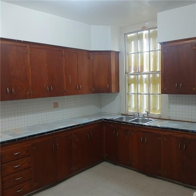 1322 Kerlerec St, New Orleans, LA 70116 - kitchen featuring tile countertops, a sink, and backsplash