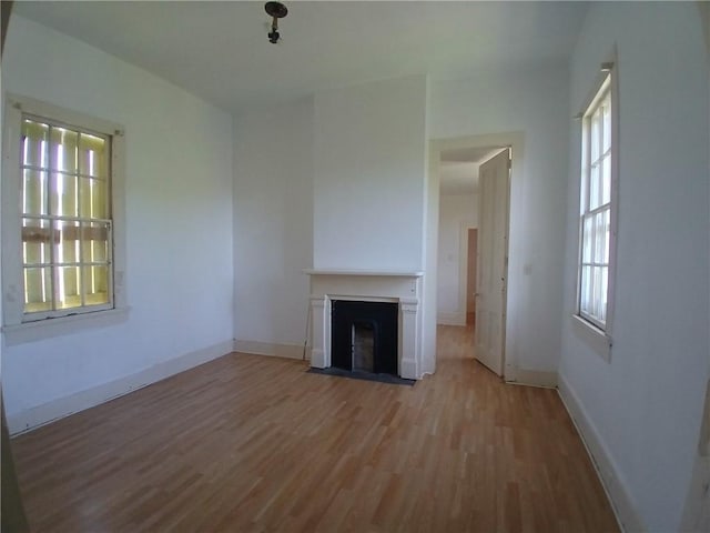 1322 Kerlerec St, New Orleans, LA 70116 - unfurnished living room with wood finished floors, healthy amount of natural light, a fireplace with flush hearth, and baseboards