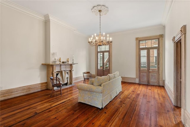 living area featuring a notable chandelier, wood-type flooring, and crown molding