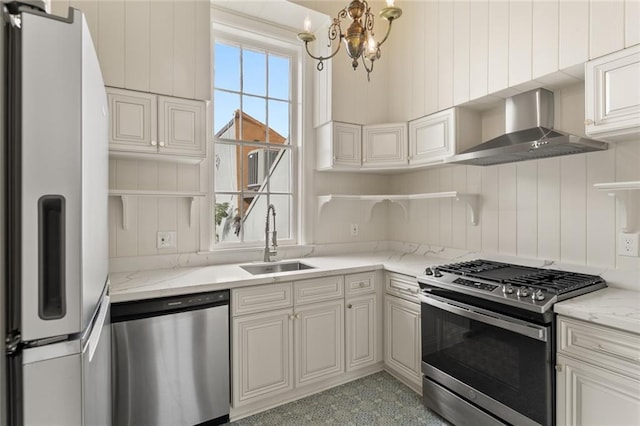 kitchen featuring sink, wall chimney exhaust hood, stainless steel appliances, light stone counters, and a notable chandelier