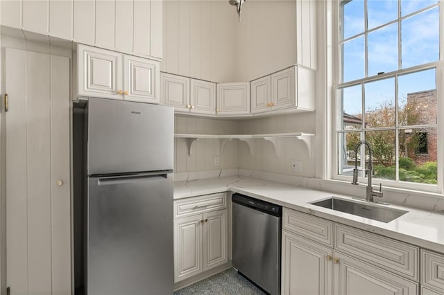 kitchen featuring white cabinetry, sink, light stone countertops, and stainless steel appliances