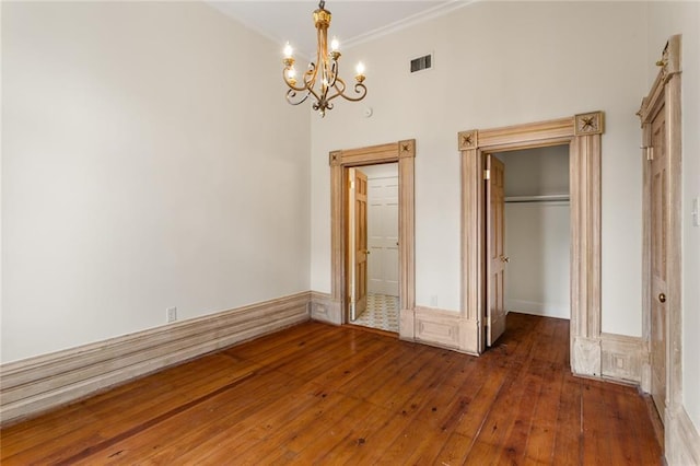 unfurnished bedroom with dark hardwood / wood-style flooring, a closet, and a notable chandelier