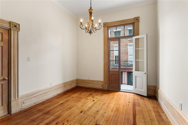 unfurnished room with a chandelier, light wood-type flooring, and crown molding