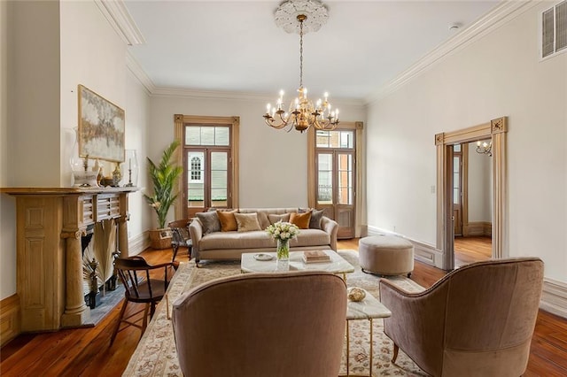 living room with a fireplace, wood-type flooring, crown molding, and a notable chandelier