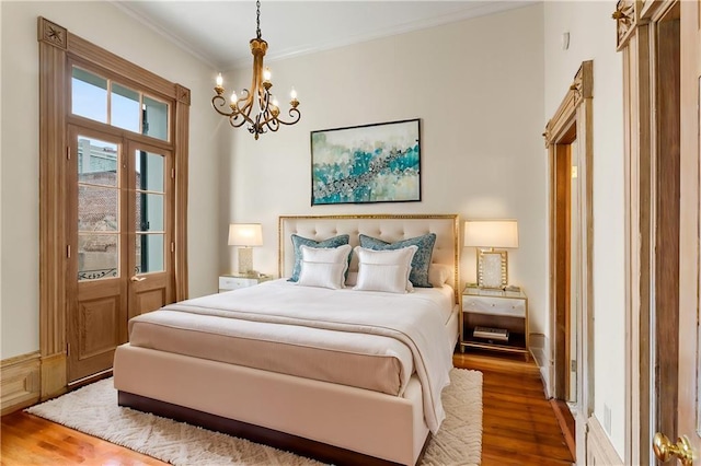 bedroom featuring hardwood / wood-style flooring, crown molding, and an inviting chandelier