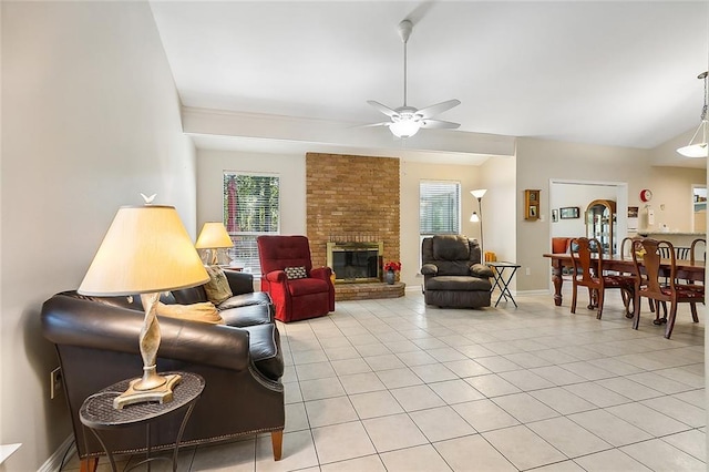 tiled living room with a fireplace, brick wall, and ceiling fan