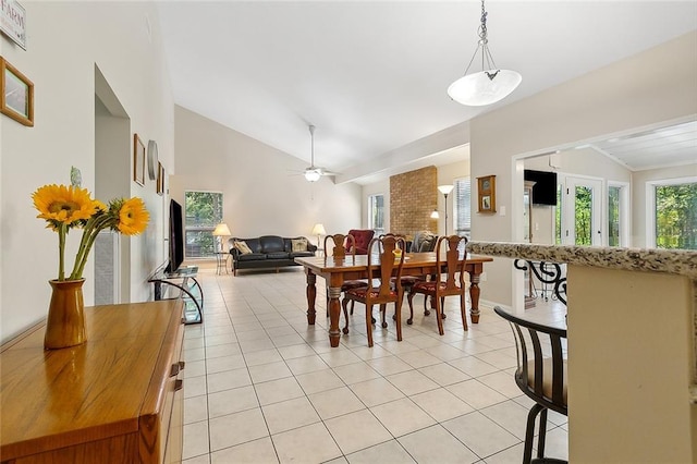 tiled dining room featuring ceiling fan, brick wall, and vaulted ceiling