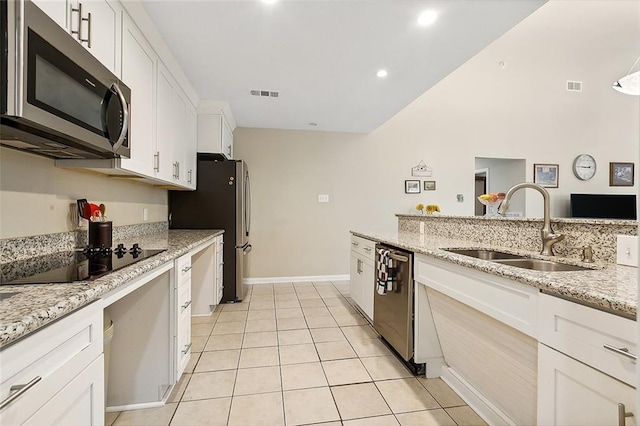 kitchen with sink, light tile floors, light stone counters, white cabinets, and appliances with stainless steel finishes