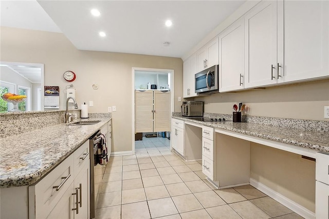 kitchen with sink, light tile floors, light stone counters, appliances with stainless steel finishes, and white cabinetry