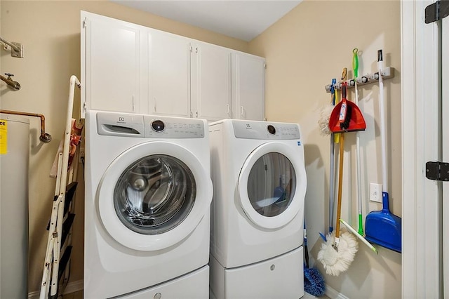 clothes washing area with independent washer and dryer, cabinets, and water heater