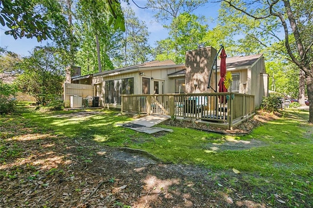 rear view of property featuring a wooden deck and a yard