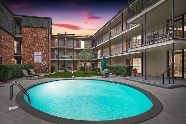 pool at dusk featuring a patio