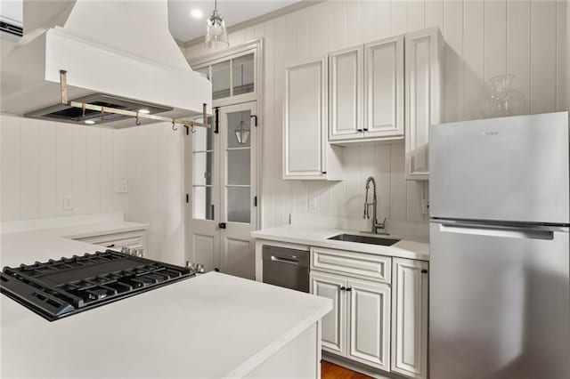 kitchen featuring gas cooktop, custom exhaust hood, sink, black dishwasher, and stainless steel refrigerator