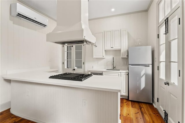 kitchen featuring kitchen peninsula, stainless steel appliances, custom range hood, and light hardwood / wood-style floors