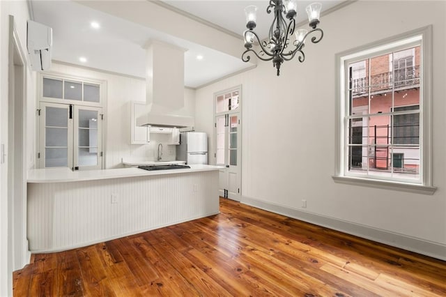 kitchen with ornamental molding, custom range hood, wood-type flooring, white fridge, and white cabinetry