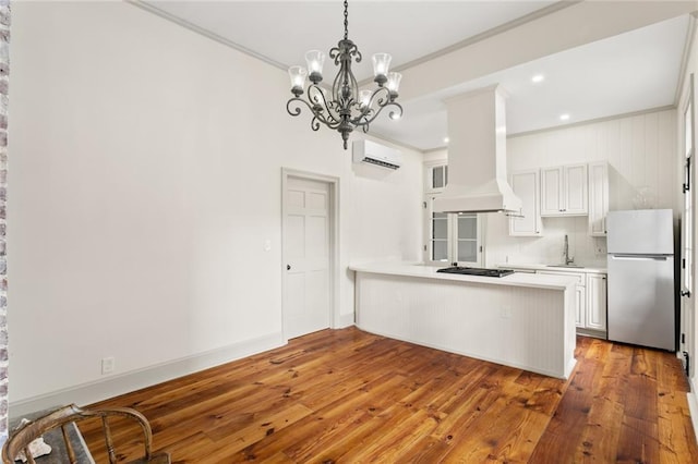 kitchen with white cabinets, hardwood / wood-style flooring, kitchen peninsula, and stainless steel refrigerator