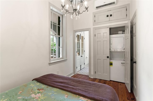 bedroom with stacked washer / dryer, a chandelier, a wall mounted AC, and dark hardwood / wood-style floors