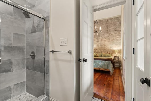 bathroom with an enclosed shower, a notable chandelier, and hardwood / wood-style flooring