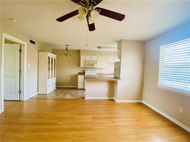 kitchen with stainless steel refrigerator, range, light hardwood / wood-style floors, ceiling fan with notable chandelier, and white cabinets