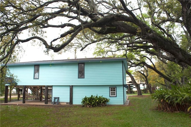 view of side of property with a patio and a lawn