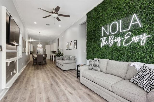 living room featuring light hardwood / wood-style floors, ceiling fan, and crown molding