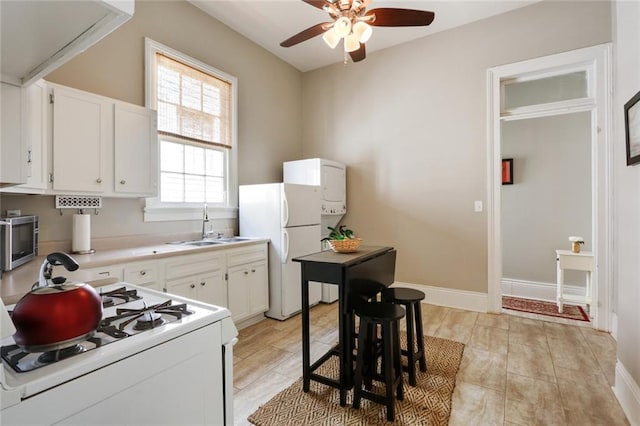 kitchen featuring ceiling fan, white cabinetry, a healthy amount of sunlight, and stove