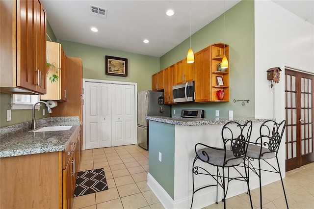 kitchen featuring light stone countertops, stainless steel appliances, pendant lighting, sink, and light tile flooring