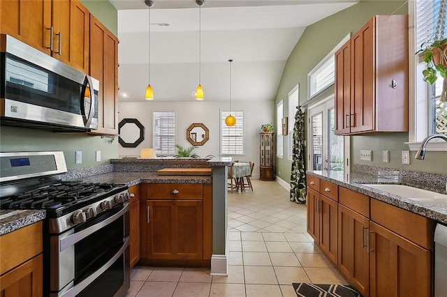 kitchen with appliances with stainless steel finishes, light tile floors, decorative light fixtures, sink, and vaulted ceiling