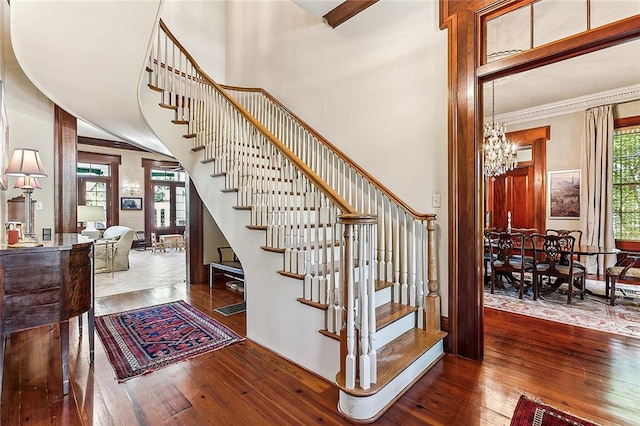 staircase with dark hardwood / wood-style floors, a notable chandelier, and a towering ceiling