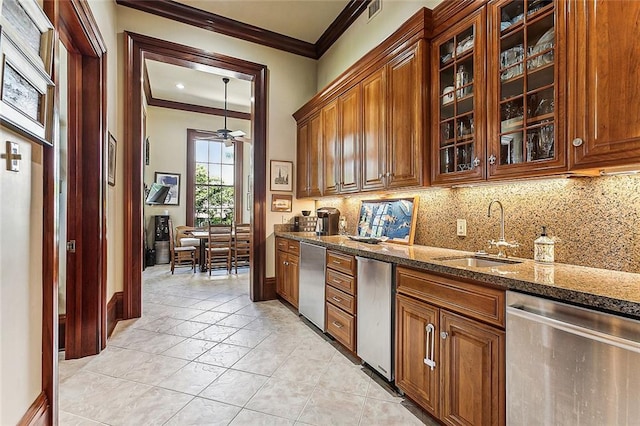 kitchen with ceiling fan, sink, dark stone counters, stainless steel dishwasher, and ornamental molding