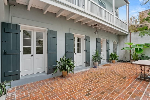 view of exterior entry with a patio area and a balcony