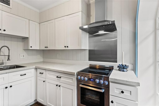 kitchen featuring stainless steel electric range oven, sink, wall chimney exhaust hood, white cabinets, and ornamental molding