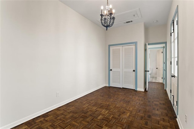 unfurnished room featuring dark parquet floors and a chandelier