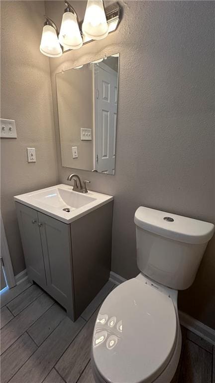 bathroom featuring toilet, vanity, and hardwood / wood-style floors