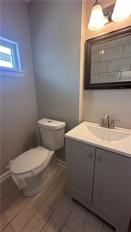 bathroom with wood-type flooring, vanity, and toilet