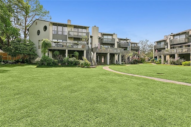 back of house with a balcony and a yard