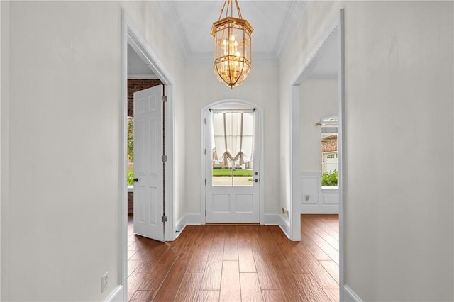 foyer with baseboards, a chandelier, crown molding, and hardwood / wood-style flooring