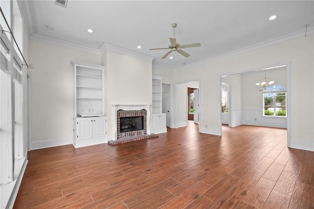 unfurnished living room with ceiling fan with notable chandelier, a brick fireplace, ornamental molding, and wood finished floors