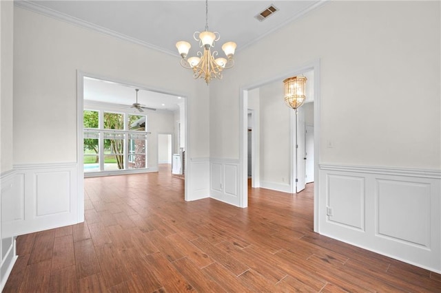 unfurnished dining area with a wainscoted wall, wood finished floors, visible vents, and ornamental molding