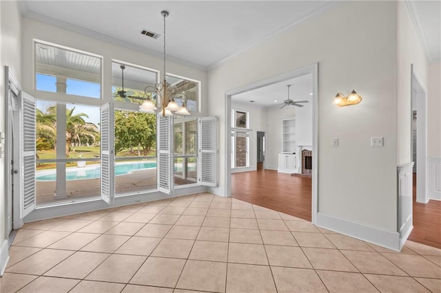 unfurnished dining area with visible vents, light tile patterned flooring, crown molding, and ceiling fan with notable chandelier