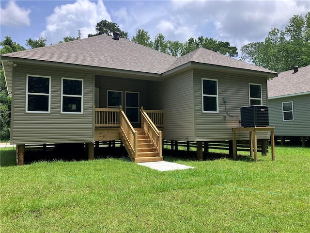 back of house with central AC unit and a yard