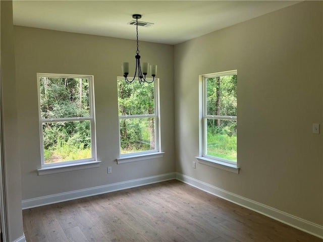 unfurnished dining area with hardwood / wood-style floors and a notable chandelier