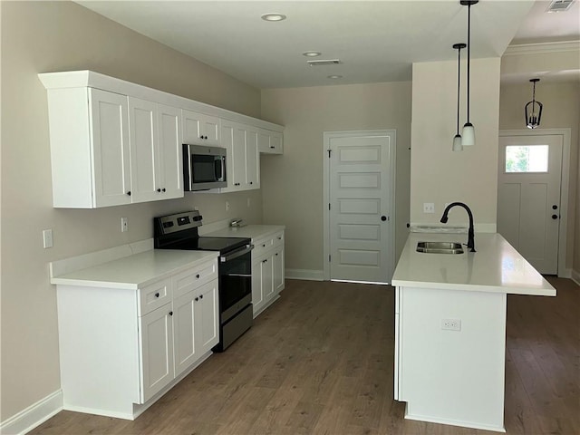 kitchen featuring pendant lighting, sink, white cabinets, stainless steel appliances, and a center island with sink