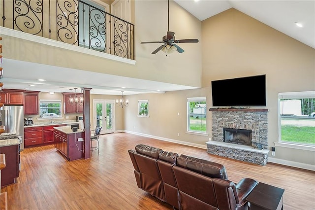 kitchen featuring light stone counters, appliances with stainless steel finishes, tasteful backsplash, hanging light fixtures, and light hardwood / wood-style flooring